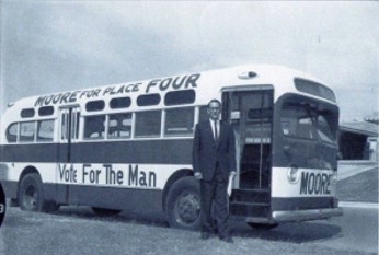 Image of Charles B. Moore (1964), in front of his campaign bus when he ran for the Texas House of Representatives.