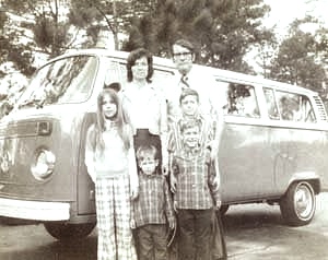 Image of Charles and Judy Moore with the kids in front of their VW bus.